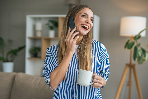 istock Woman talking on phone smiling and drinking coffee at home 2247366874