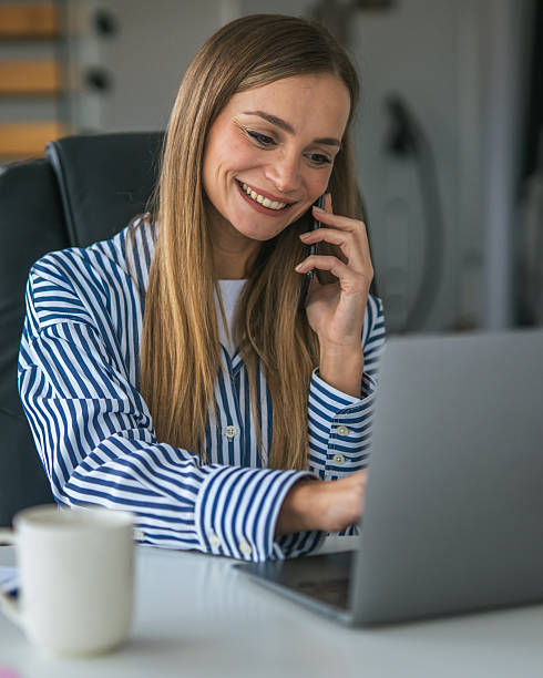 istock Young woman smiling, multitasking with a phone call and laptop 2247367262