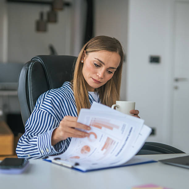 istock Woman working from home reviewing documents drinking coffee 2247367325