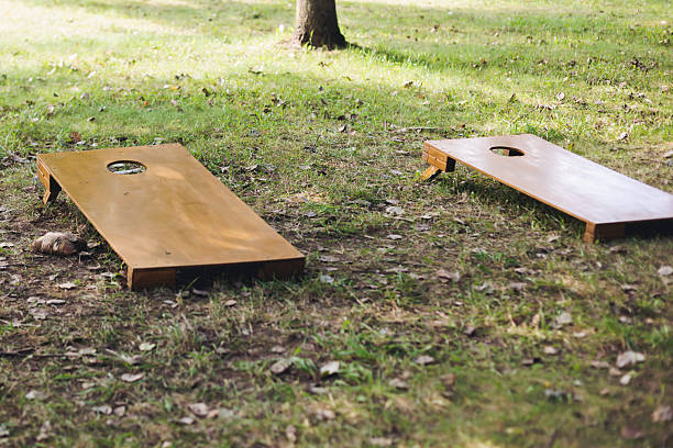 istock Cornhole game set, process of throwing bean bags, kids children with parents tossing bean sacks, backyard lawn corn hole , wooden boards for corn-hole tournament in the summer sunny day in a city park 2247367952