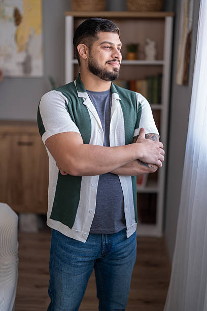 istock Young man smiling looking out window at home 2247369357
