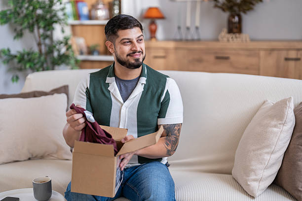 istock Satisfied man unboxing new clothes purchased online at home 2247369370