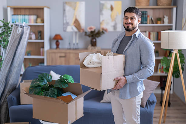 istock Man smiling holding moving box in new home 2247369418