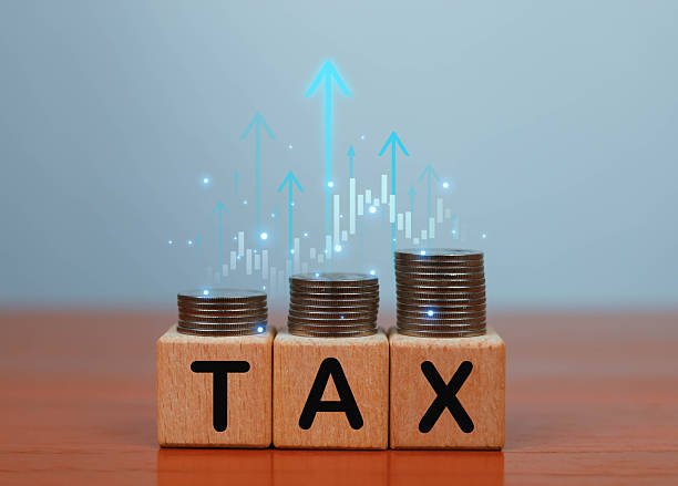 istock Stacked coins on wooden blocks spelling TAX with rising financial graph elements, representing tax increase, financial growth, economic planning, investment strategy, and fiscal management concepts. 2247370096