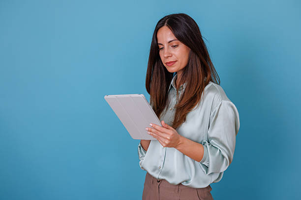 istock Woman working with digital tablet on blue background, engaging with technology for business and professional tasks 2247372799
