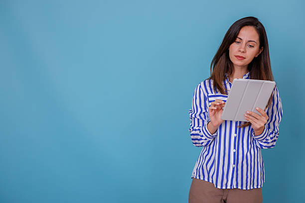 istock Young adult woman using a digital tablet, interacting with technology against a vibrant blue background 2247374373