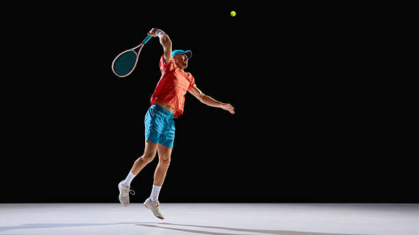 istock Focused tennis player jumping for powerful serve on dark background 2247375979