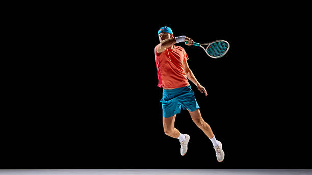 istock Athletic man jumping for strong tennis shot in professional studio lighting 2247375993