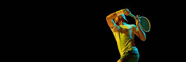 istock Tennis player in motion swinging racket under dramatic colored lighting. Banner 2247375996