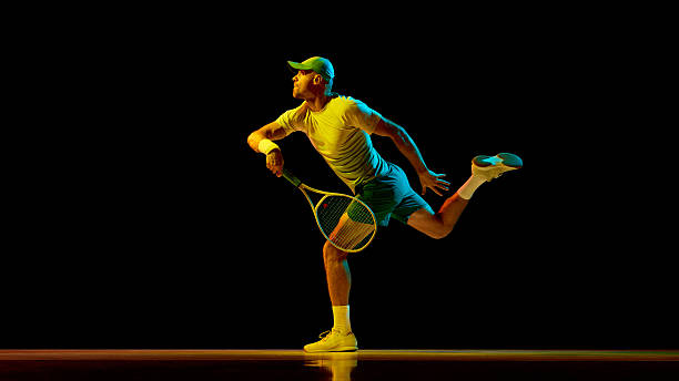 istock Tennis player stretching to hit low ball under neon light with focus 2247376014