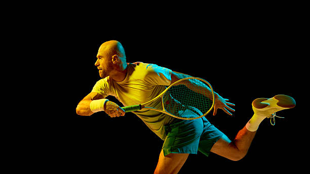 Energetic tennis player hitting forehand illuminated by cinematic lighting