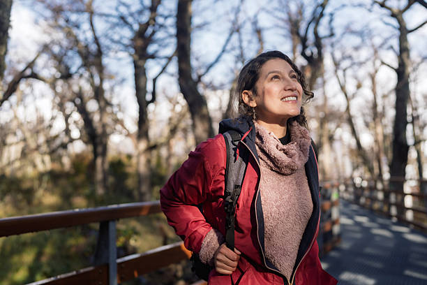 Happy woman hiking, smiling, looking up while walking on a boardwalk through the forest near perito moreno glacier