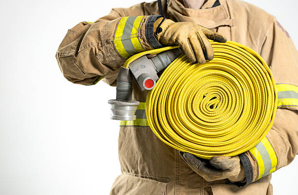 Close-up of water flowing from a yellow fire hose onto a wet street surface, illustrating firefighting and emergency response equipment in urban settings.