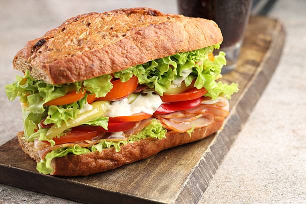 istock Delicious baguette sandwich with tomatoes and yellow beans on grey textured table, closeup 2247381013