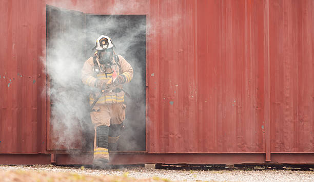 istock A firefighter in full protective gear runs out of a smoke-filled structure carrying an emergency axe 2247381104