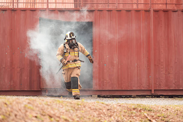 istock A firefighter in full protective gear runs out of a smoke-filled structure carrying an emergency axe 2247381106
