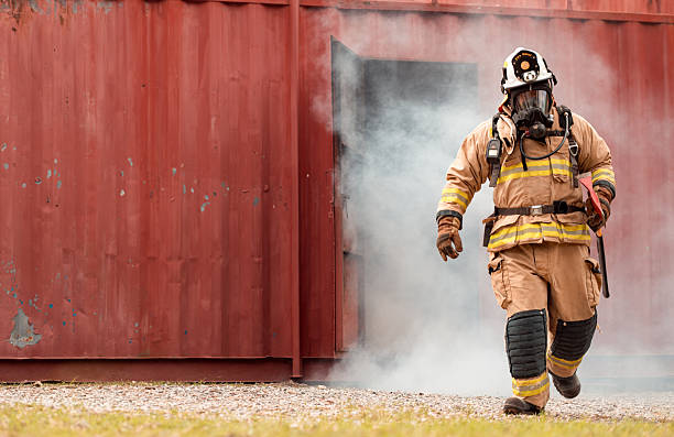 istock A firefighter in full protective gear runs out of a smoke-filled structure carrying an emergency axe 2247381109