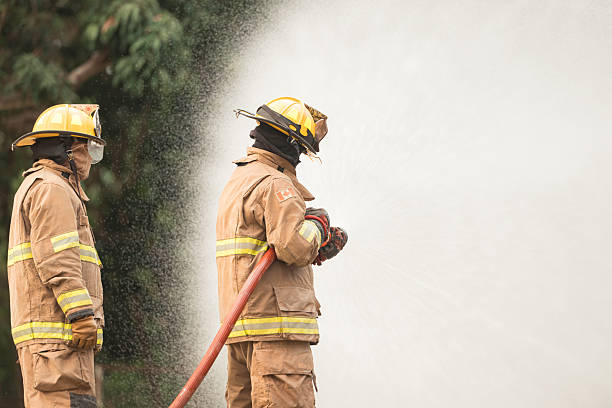 istock Two firefighters standing in position while directing a powerful water stream at a large blaze 2247381496