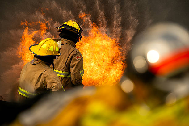 istock Two firefighters standing in position while directing a powerful water stream at a large blaze 2247381520