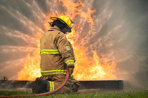 istock Two firefighters kneel in position while directing a powerful water stream at a large blaze 2247381528