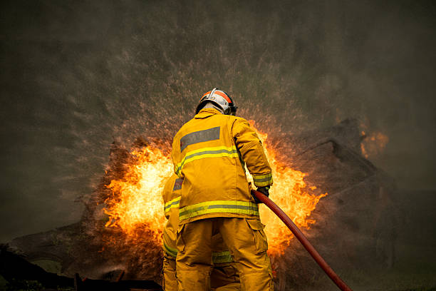 istock Two firefighters standing in position while directing a powerful water stream at a large blaze 2247381546