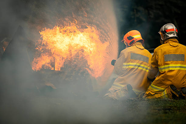 istock Two firefighters kneel in position while directing a powerful water stream at a large blaze 2247381548
