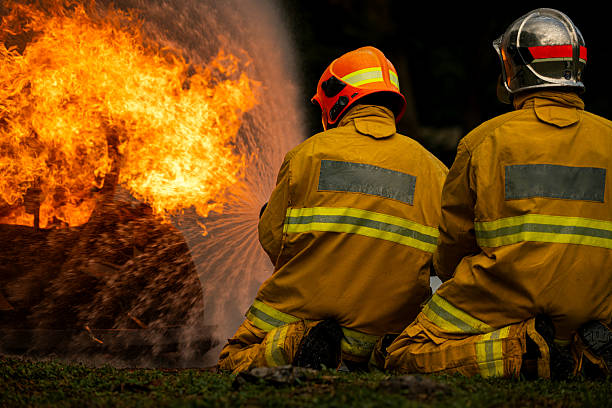 istock Two firefighters kneel in position while directing a powerful water stream at a large blaze 2247381558
