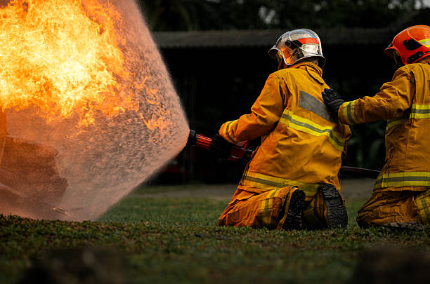 istock Two firefighters kneel in position while directing a powerful water stream at a large blaze 2247381586
