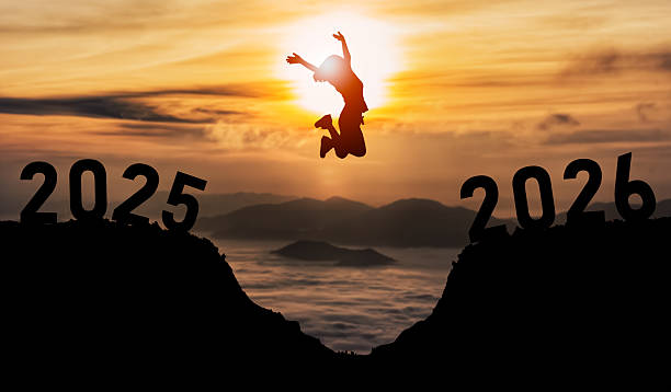 istock Person leaps joyfully between two years, representing transition and new beginnings, with a stunning sunset in the background over mountains and clouds. 2247384984