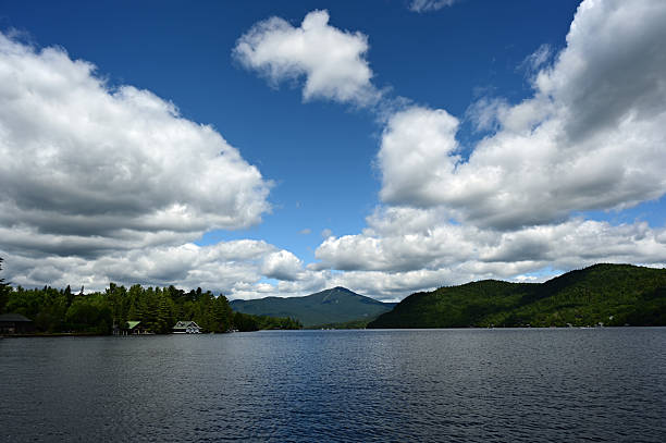 Bright summer cloudscape over Lake Placid, New York State on sunny afternoon with Adirondack Mountains in background.