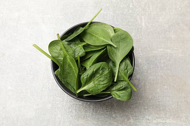 istock Fresh spinach leaves in bowl on light textured table, top view 2247391916