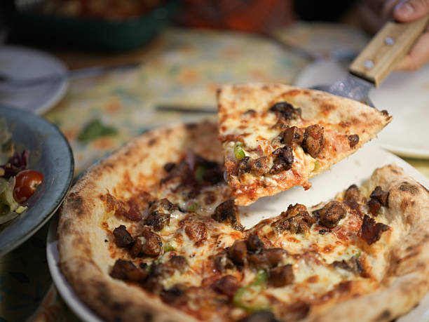 istock A delicious pizza being served with a slice lifted by a spatula at a cozy dining table 2247398508