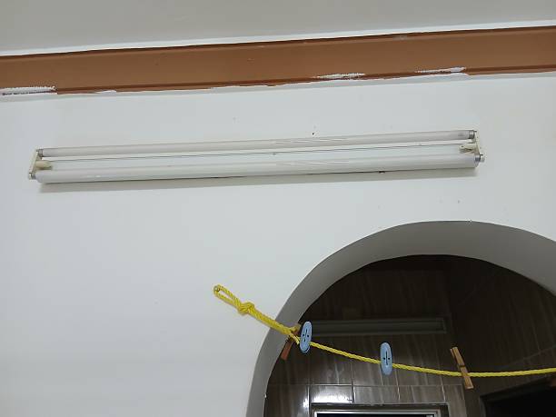 istock Two fluorescent light bulbs, a white clothesline, clothespins, and a white and brown wall 2247400592
