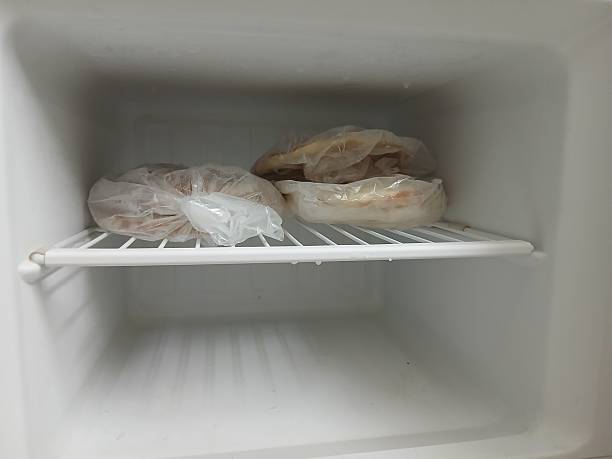istock Bread in plastic bags in an empty white refrigerator freezer 2247400633