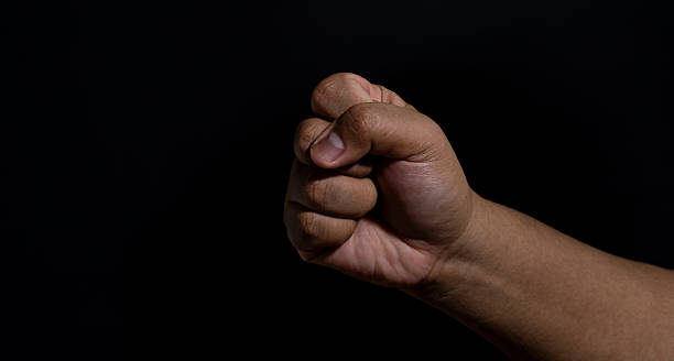 istock Hand forming a tight fist with highlighted contours and deep shadows, conveying strength, tension, and focused energy in a minimalist dark studio setup. 2247401768