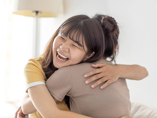 istock Happy asian girls embraced in a friendly hug 2247402538