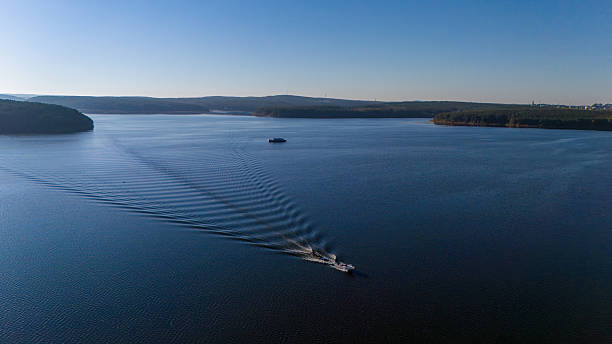 istock A speedboat creates ripples on the calm lake surface, with serene forests and blue sky in the distance 2247403035