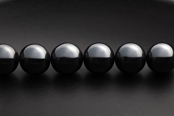 istock Row of Glossy Black Magnetic Spheres on Dark Background 2247404036