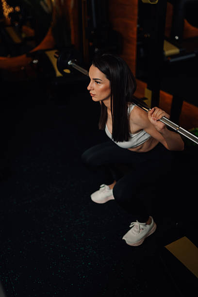 istock Determined sportswoman performing squats with barbell in gym 2247407456