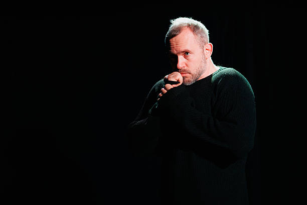 istock Actor in sweatshirt gesturing on black background in theater 2247411877