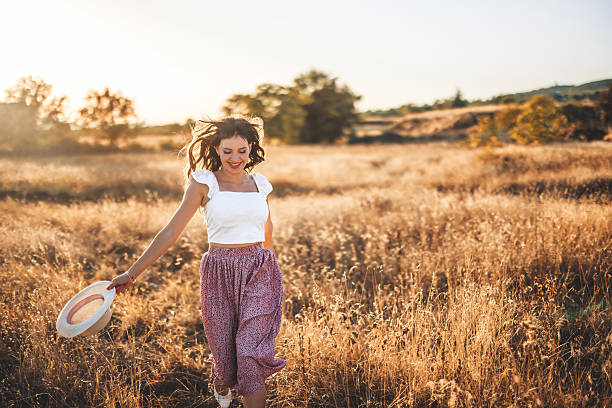 istock Young Woman Running In The Field At Sunset While Holding A Hat 2247413064