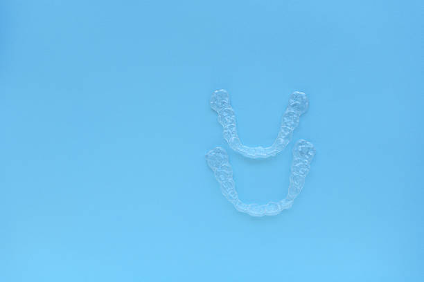 Clear aligners placed neatly on blue background, showcasing their transparent design and modern orthodontic technology. Clean minimal composition suitable for dental care and oral health themes