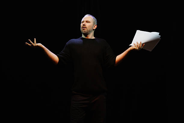istock Actor with scenario gesturing on black background in theater 2247413830