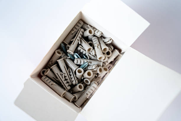 Open box filled with assorted wall plugs and screws on a white background. Construction and home repair supplies, hardware tools. High quality photo