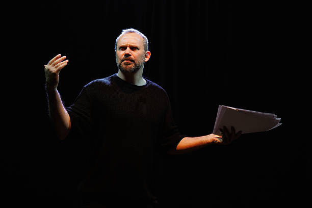 istock Actor in sweatshirt holding papers during rehearsal on theater stage 2247414613