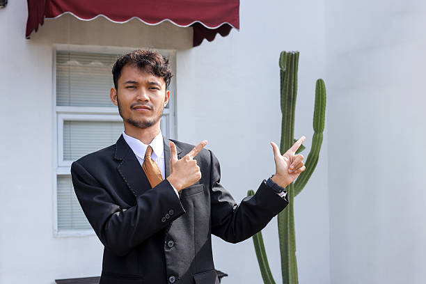 Confident Young Businessman Pointing to Either Side in Outdoor Setting