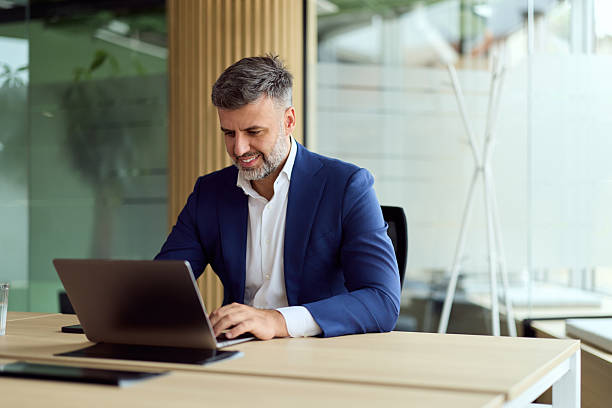 istock Professional Man In Blue Suit Working On Laptop In Modern Office Space 2247415311