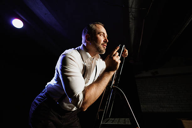 Actor in white shirt performing on ladder on stage