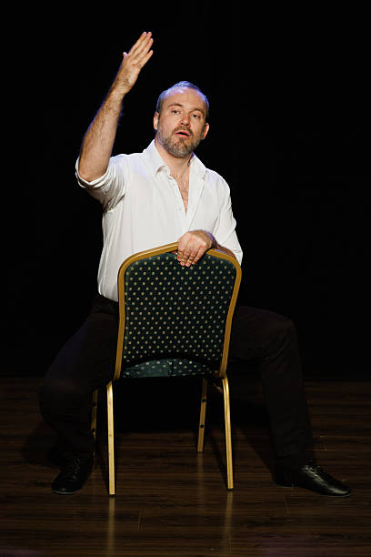 istock Actor in white shirt talking while sitting on chair on theater stage 2247417089