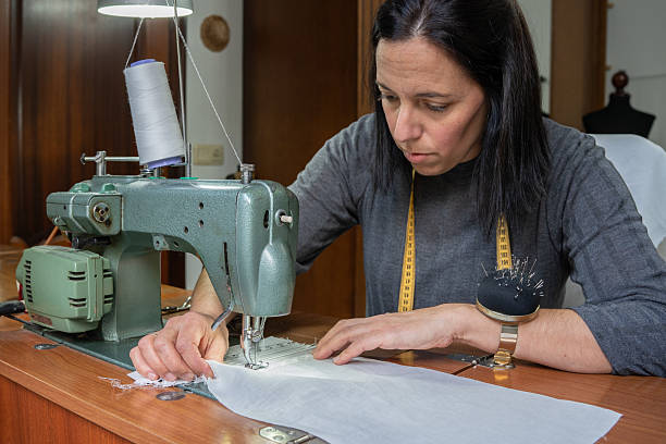 Woman focusing on sewing garment with fabric at her home studio